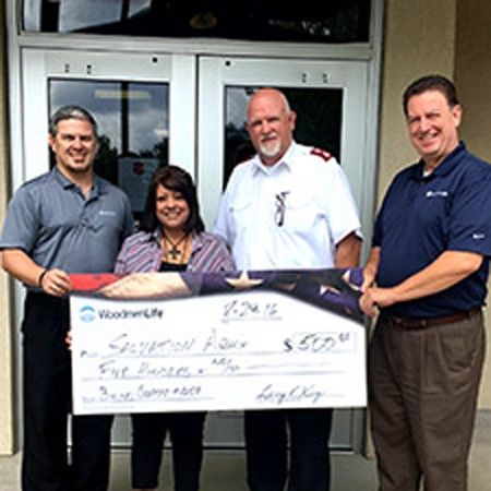 A picture of 4 adults holding a large novelty check made out to the Salvation Army for the amount of $500 from WoodmenLife