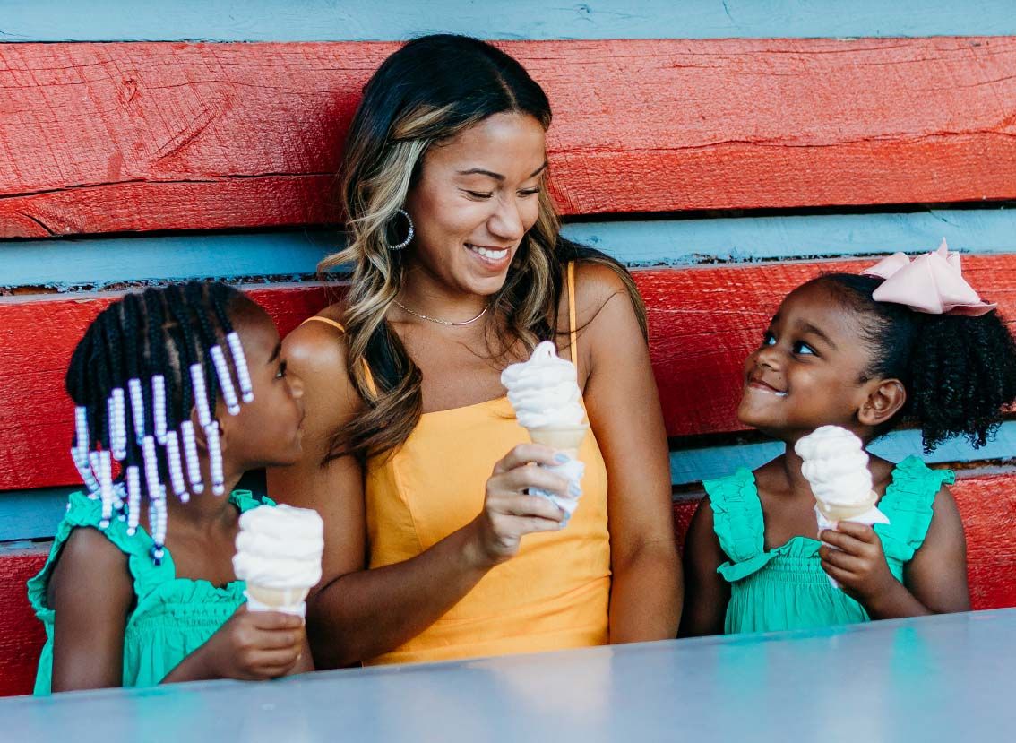 A mother and her two young daughters enjoy ice cream cones