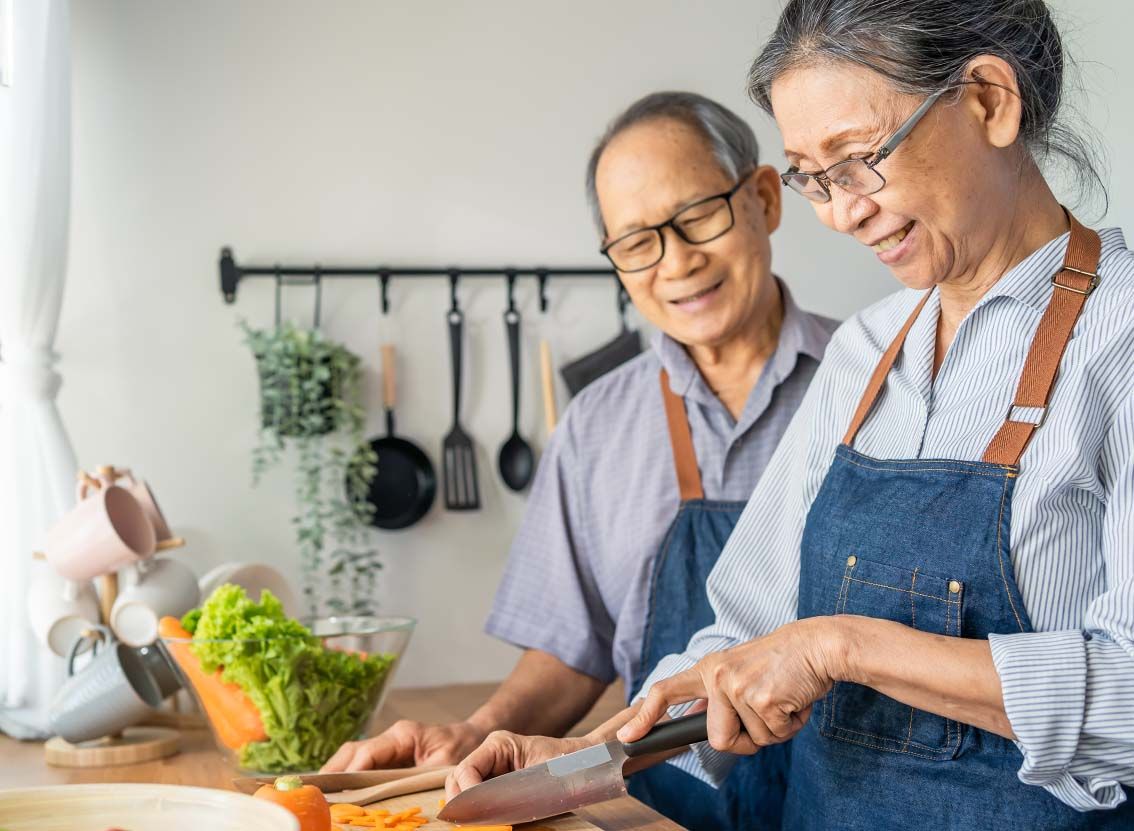 Older Asian couple preparing a meal together.