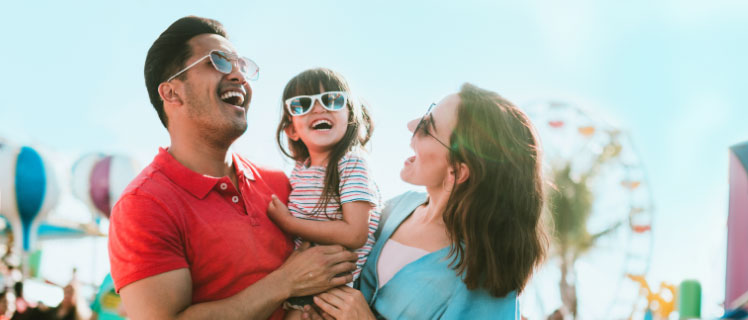 A family of three laughing at a carnival